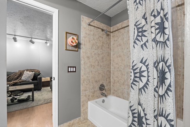 bathroom with a textured ceiling, hardwood / wood-style flooring, shower / bath combination with curtain, and rail lighting