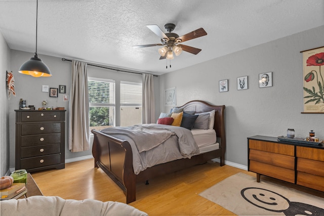 bedroom featuring light hardwood / wood-style floors, a textured ceiling, and ceiling fan