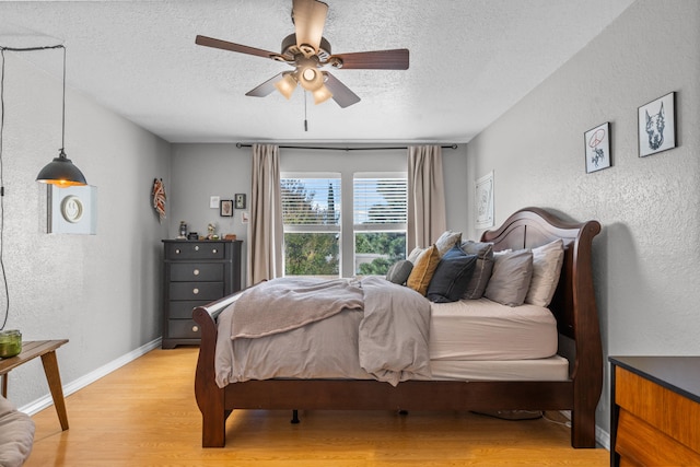 bedroom featuring light hardwood / wood-style flooring, a textured ceiling, and ceiling fan