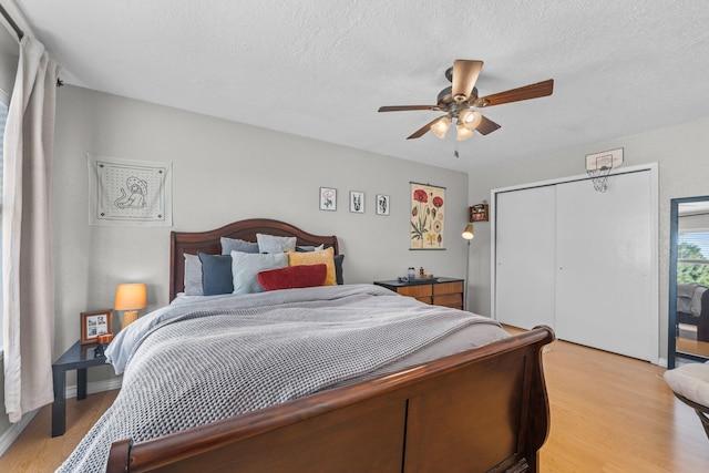 bedroom with a closet, light hardwood / wood-style floors, a textured ceiling, and ceiling fan