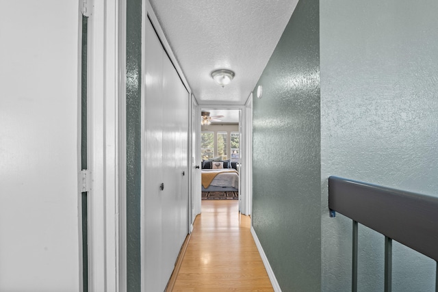 hallway featuring light hardwood / wood-style flooring and a textured ceiling