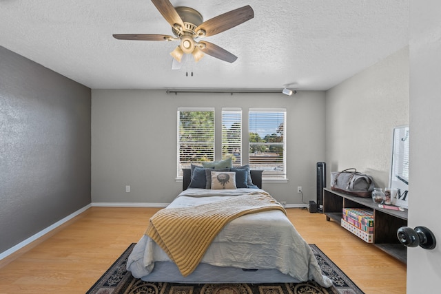 bedroom featuring light hardwood / wood-style floors, a textured ceiling, and ceiling fan