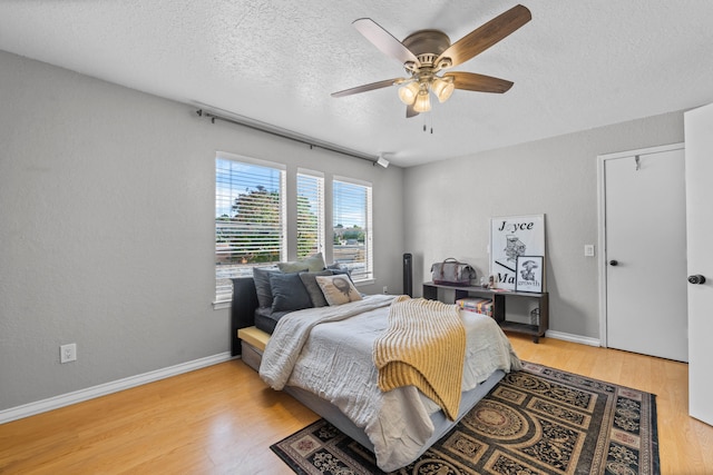 bedroom with ceiling fan, a textured ceiling, and light hardwood / wood-style flooring