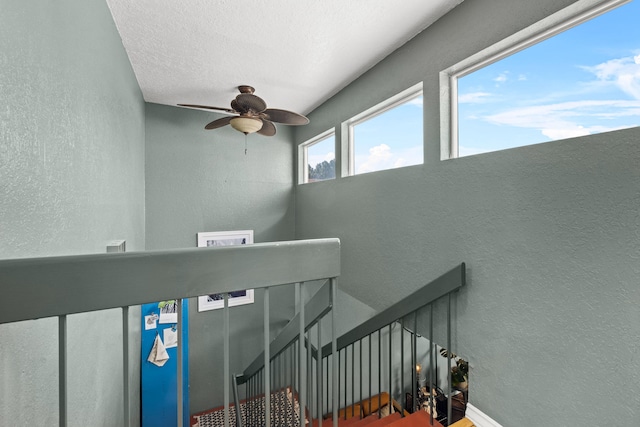 stairway with a textured ceiling and ceiling fan