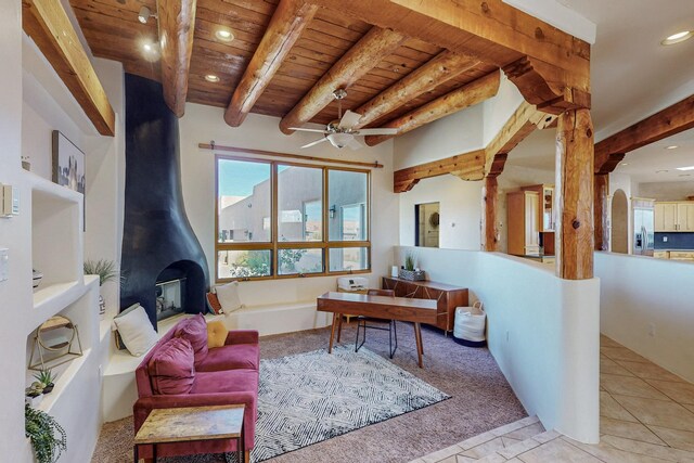 interior space featuring beam ceiling, a wood stove, ceiling fan, wooden ceiling, and light tile patterned floors