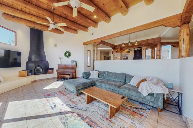 living room featuring ceiling fan, light tile patterned floors, beam ceiling, wooden ceiling, and a wood stove