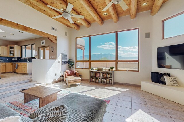 living room with beamed ceiling, light tile patterned floors, a towering ceiling, and wooden ceiling