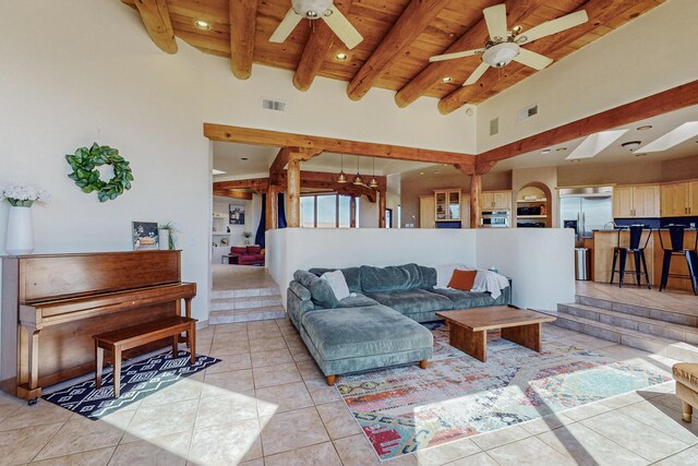 tiled living room featuring beam ceiling, a towering ceiling, ceiling fan, and wood ceiling