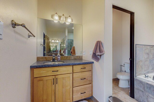 bathroom with tile patterned floors, vanity, toilet, and tiled tub