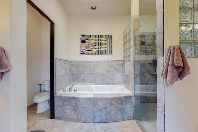 bathroom featuring toilet, tile patterned flooring, and shower with separate bathtub