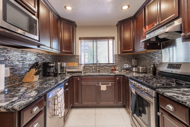 kitchen featuring tasteful backsplash, dark stone countertops, sink, light tile patterned flooring, and appliances with stainless steel finishes