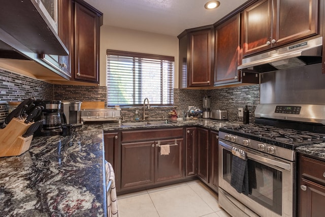 kitchen featuring decorative backsplash, dark stone counters, gas stove, and sink