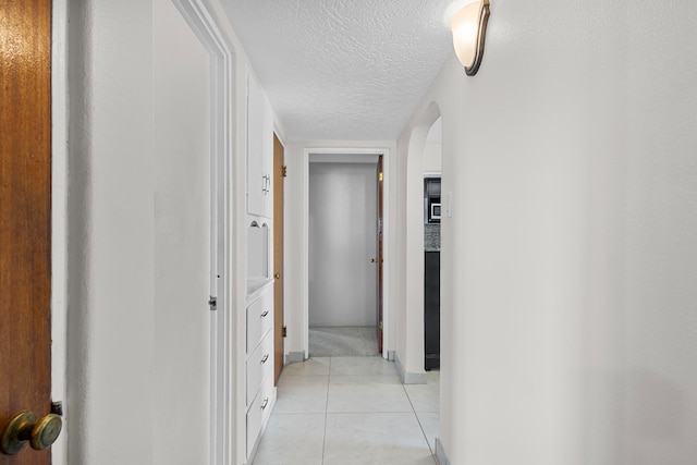 hall with light tile patterned floors and a textured ceiling