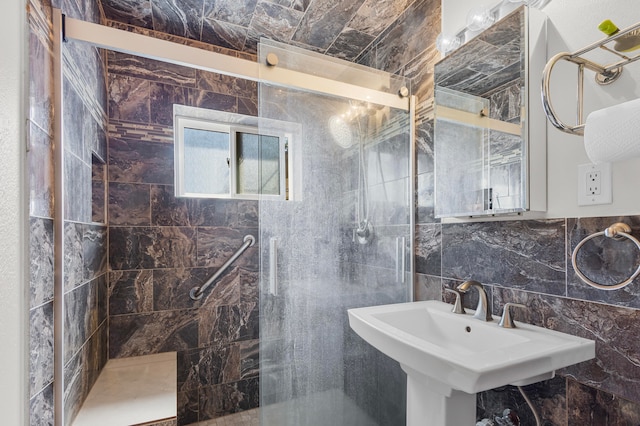 bathroom with tile walls, sink, a shower with door, and tasteful backsplash