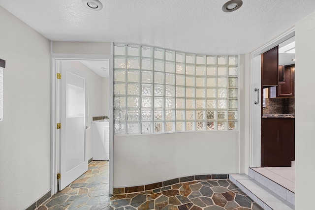 bathroom with washer / clothes dryer and a textured ceiling