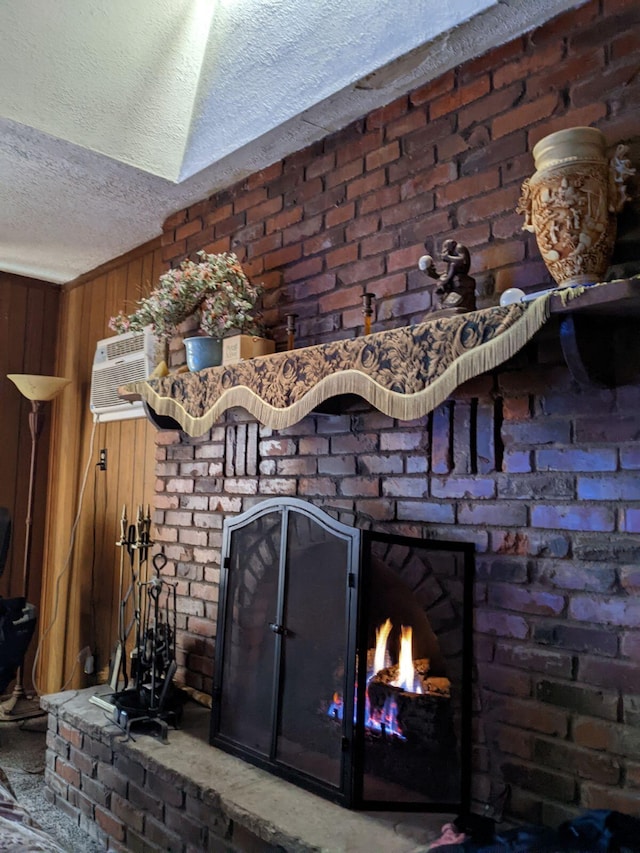 details featuring a brick fireplace, wooden walls, a wall mounted AC, and a textured ceiling