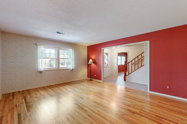 empty room featuring light wood-type flooring and a textured ceiling