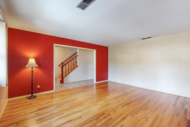 empty room with hardwood / wood-style flooring and a textured ceiling