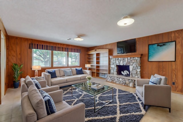 tiled living room with a fireplace, wood walls, and a textured ceiling