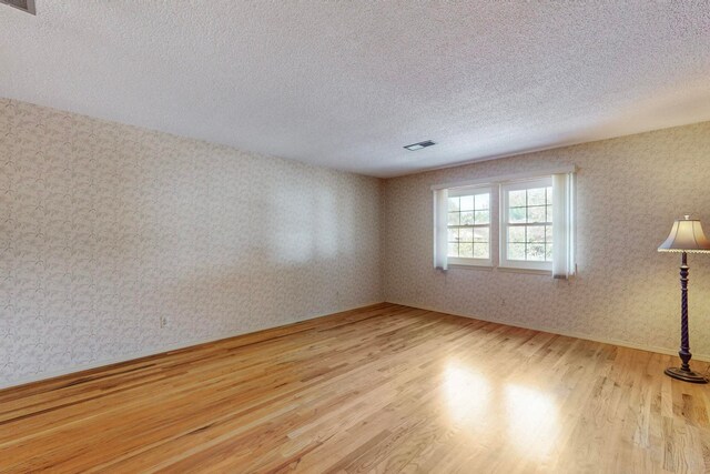 spare room featuring a textured ceiling and light wood-type flooring