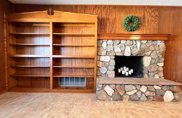 unfurnished living room with a fireplace, wood walls, a textured ceiling, and light tile patterned flooring