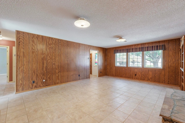 unfurnished room featuring wood walls and a textured ceiling