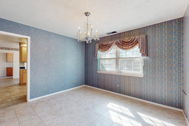 spare room with an inviting chandelier, light tile patterned floors, and a textured ceiling