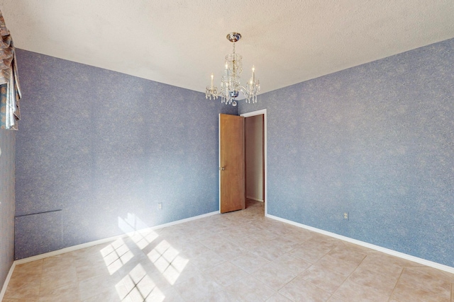 empty room featuring a textured ceiling and an inviting chandelier