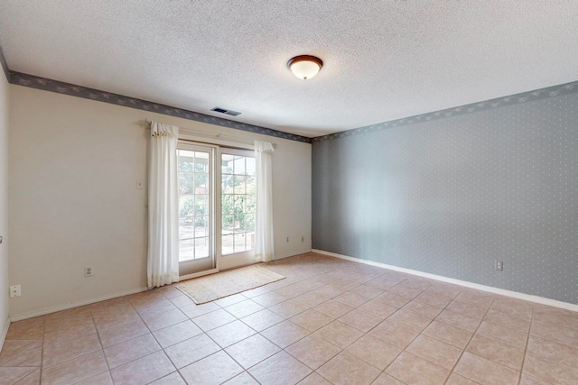 spare room with a textured ceiling and light tile patterned floors