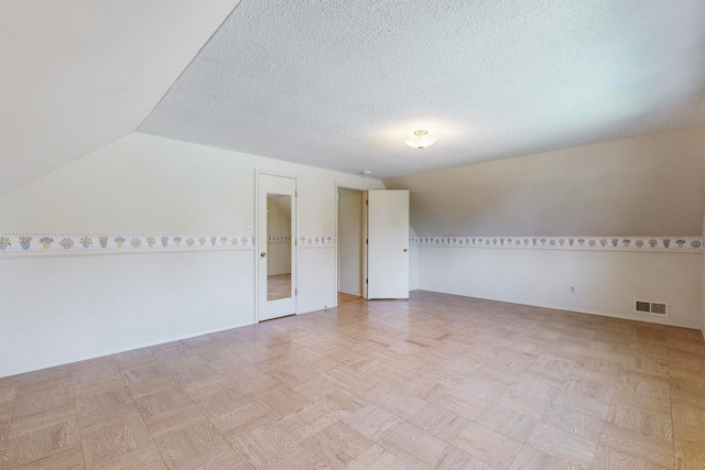 bonus room featuring lofted ceiling and a textured ceiling