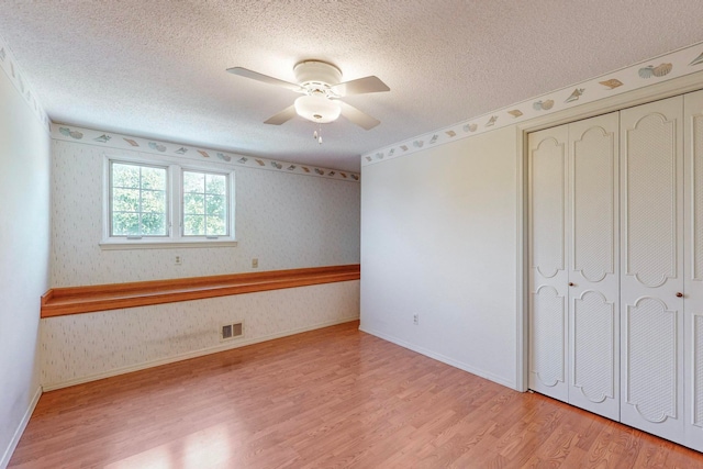 unfurnished bedroom with ceiling fan, a textured ceiling, a closet, and light hardwood / wood-style flooring