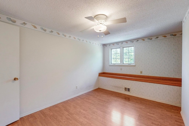 unfurnished room with wood-type flooring, ceiling fan, and a textured ceiling