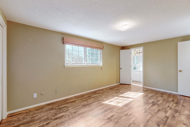 unfurnished room with a textured ceiling and light wood-type flooring