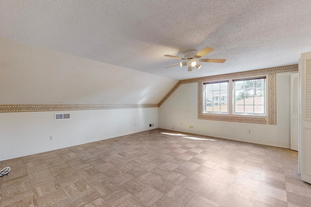 additional living space featuring a textured ceiling, ceiling fan, and vaulted ceiling