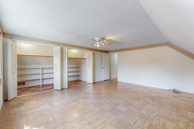 unfurnished bedroom featuring ceiling fan, a textured ceiling, and two closets