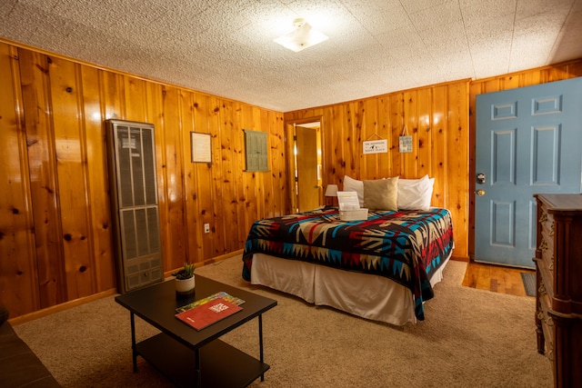 bedroom with a textured ceiling, carpet floors, and wood walls