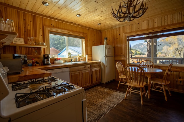 kitchen featuring wood counters, dark hardwood / wood-style floors, sink, wooden walls, and white appliances