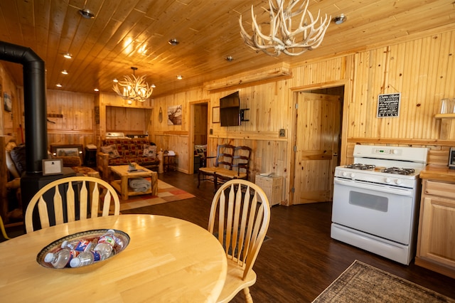 dining room featuring dark hardwood / wood-style floors, a wood stove, wooden ceiling, a chandelier, and wood walls