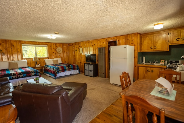 interior space with light carpet, a textured ceiling, stove, white fridge, and sink