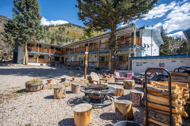 back of property featuring a balcony, a mountain view, and a fire pit