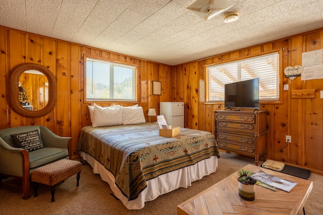 bedroom featuring carpet, white fridge, and wood walls