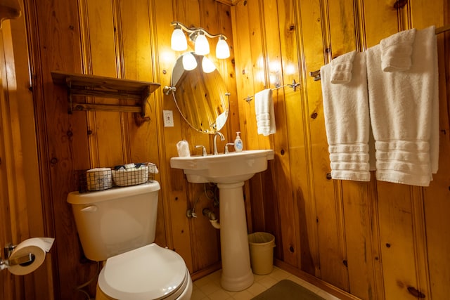 bathroom with tile patterned floors, toilet, and wood walls