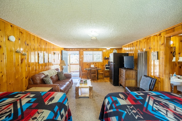 bedroom featuring stainless steel fridge, a textured ceiling, carpet flooring, and wooden walls