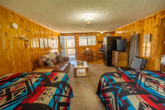 bedroom with stainless steel fridge, carpet flooring, a textured ceiling, and wooden walls