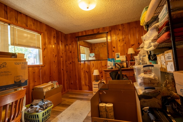 misc room with a textured ceiling, light hardwood / wood-style floors, and wood walls