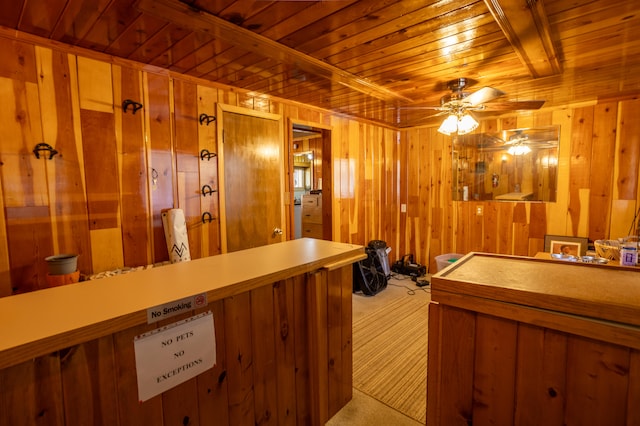 interior space featuring wooden walls, light carpet, wooden ceiling, and ceiling fan