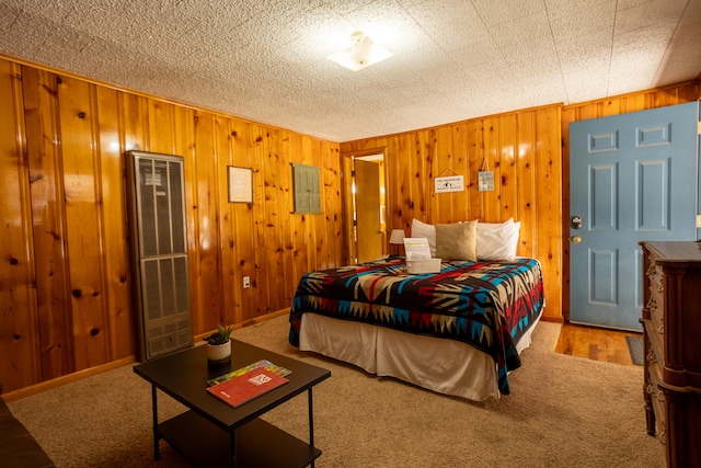 bedroom with carpet floors, wooden walls, and a textured ceiling