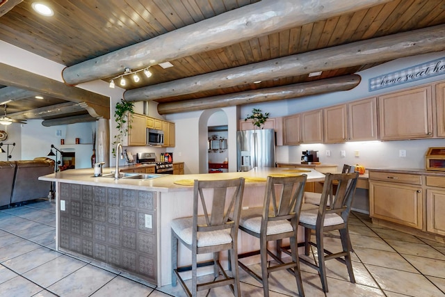 kitchen with light tile patterned floors, beamed ceiling, sink, and stainless steel appliances