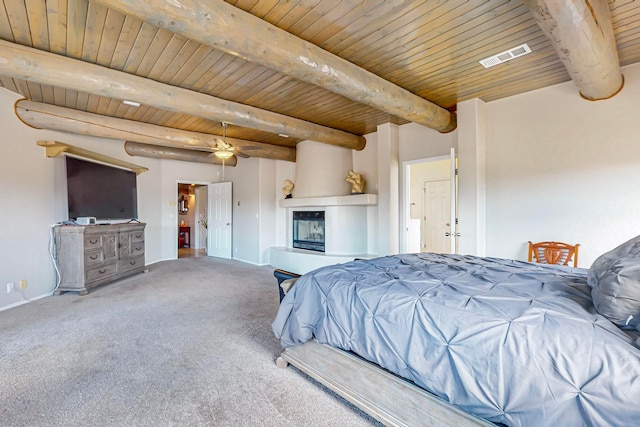 carpeted bedroom featuring a large fireplace, beamed ceiling, wood ceiling, and ceiling fan