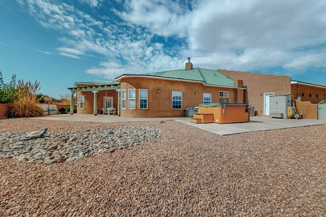 rear view of house featuring a hot tub, a patio area, and a pergola